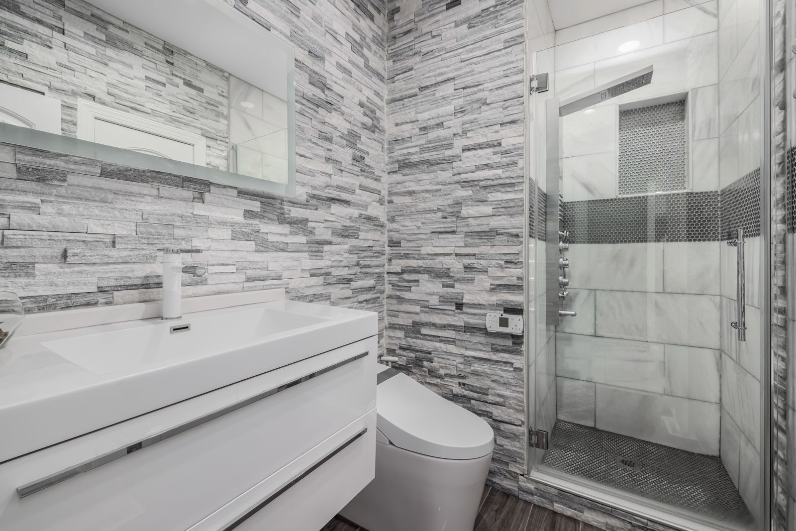A modern remodeled bathroom with a glass walk-in shower