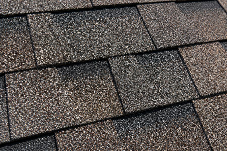 Close-up of dimensional architectural shingles with rich shadow lines and a warm multi-tone color blend