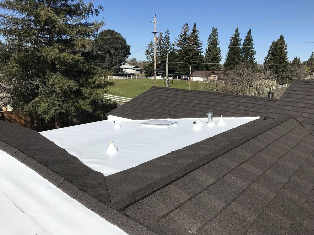Residential TPO membrane roofing installation alongside shingled roof sections